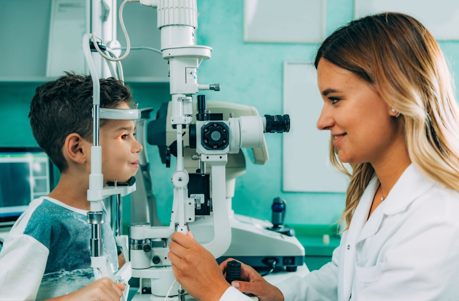 A female optometrist uses a slit lamp to examine a young boy's eyes