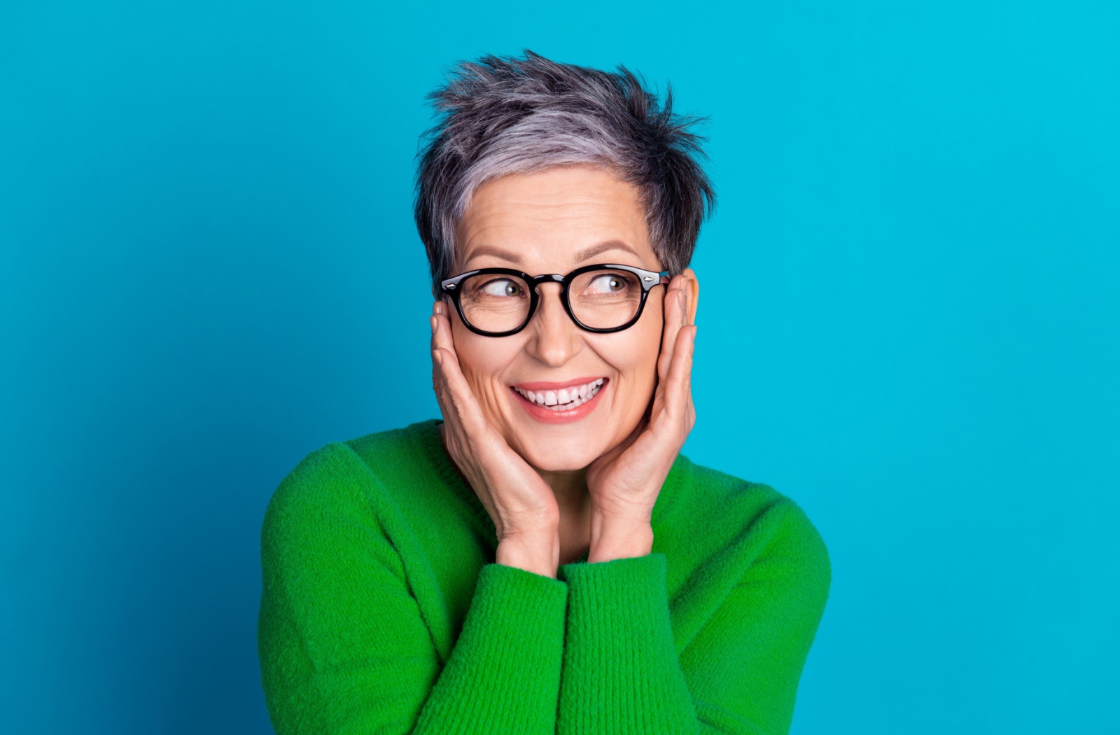 A person in front of a bright, blue background happily wears bold eyeglasses.