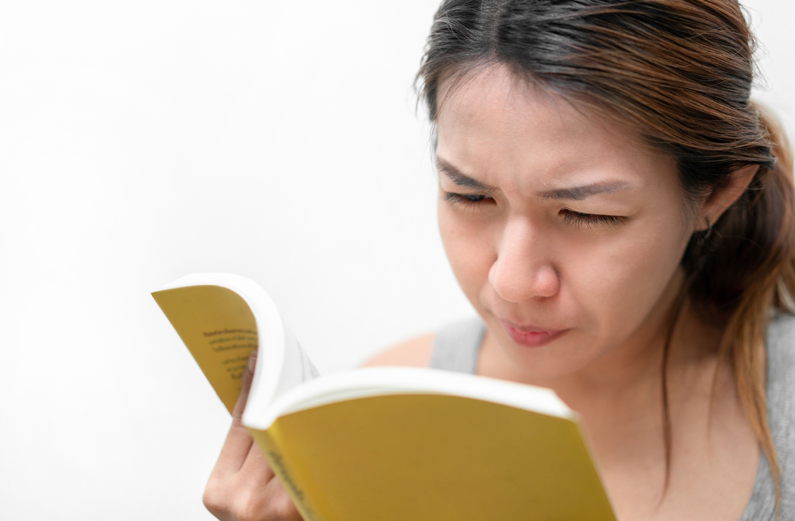 A person squinting while reading a book.
